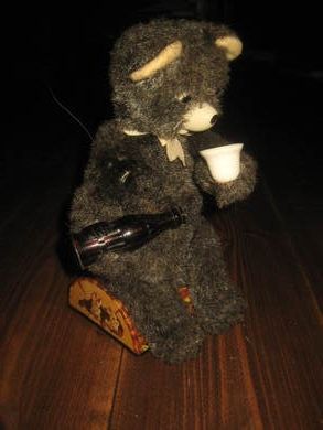 Mekanisk, japansk bamse i stol, ca 30 cm høg, batteri mangler. 50-60 tallet.