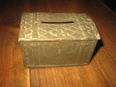 En gammel sparebørse i metall, ca 7*5 cm stor, 4 cm høg, tidleg 1900.