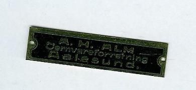 Reklameplate i messing med tekst: A.H. ALM Jernvareforretning Aalesund.