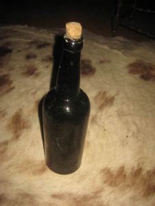 Gammel flaske, brun, tykkt glass, ca 28 cm høg, pen i glasset med sol lys gjennom flaska. 