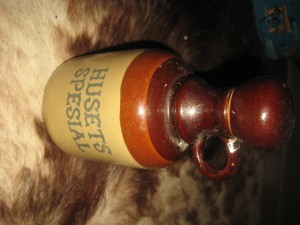 Pen keramikkflaske med tekst: HUSETS SPESIAL. Ca 21 cm høg. 