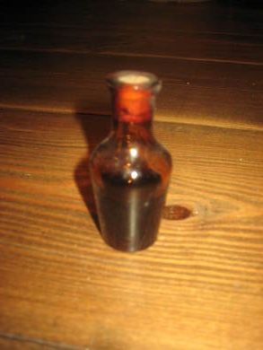 Lita flaske med ubrukt innhold ca 7 cm høg
