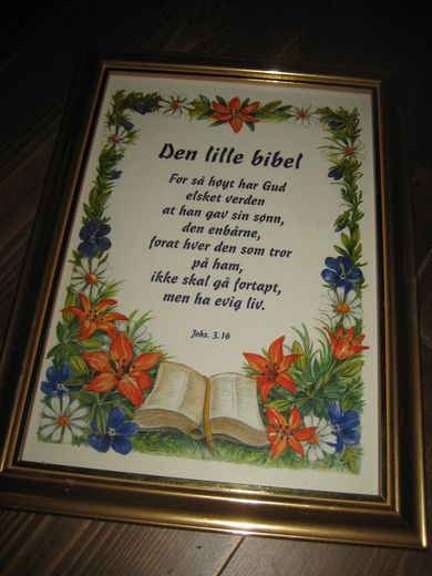 Bilde i glass og ramme med tekst: For så høyt har Gud elsket verden at han gav sin sønn den enbårne for at hvær den som tror på han ikke skal gå fortapt men ha evig liv