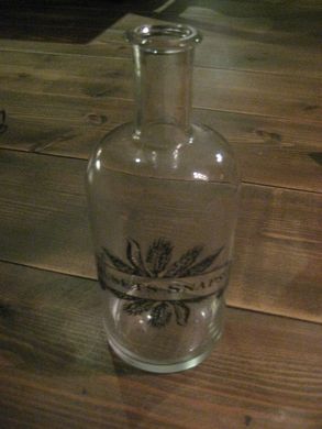 Flaske med tekst: HUSETS SNAPS Ca 21 cm høg